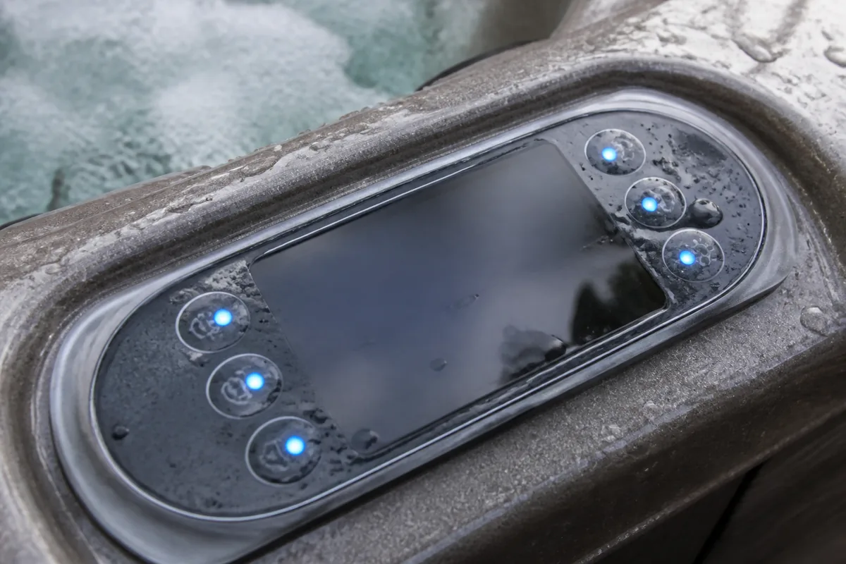 Lit hot tub control buttons beside a blank glossy topside display