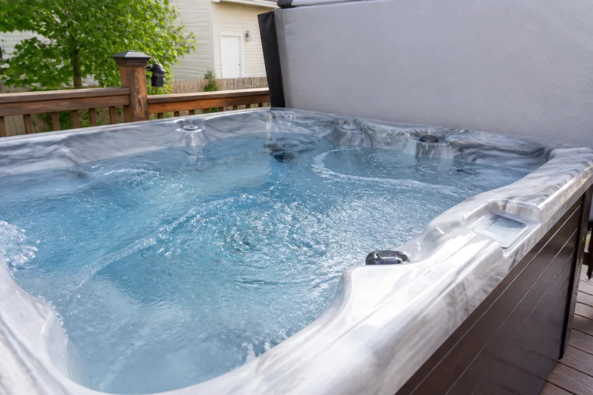 Residential hot tub with jets circulating water and the cover folded back